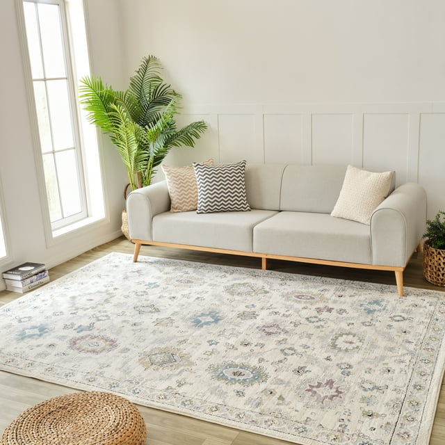 Beige cream Rug Branch Nomad Classic indoor area rug featuring subtle multicolor boho patterns placed in a bright living room under a light gray sofa with chevron and textured pillows.