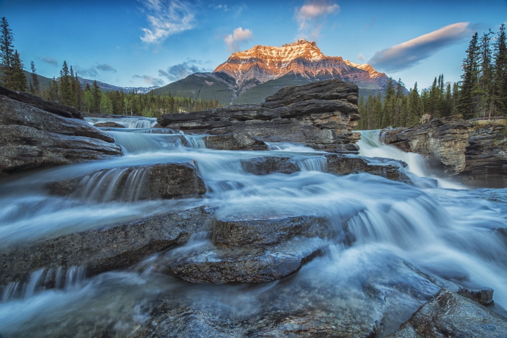 Sunset lights up Mount Fryatt as the Athabasca River flows over