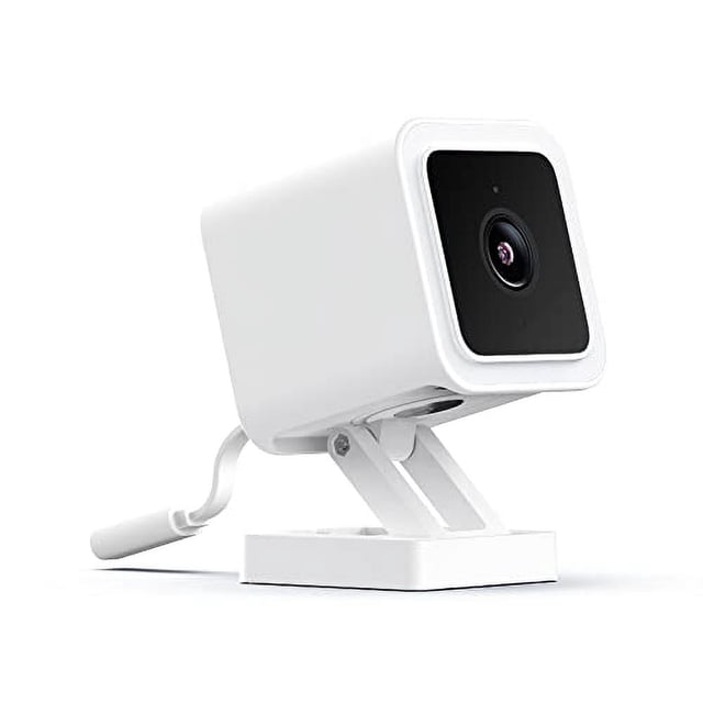 cámara de seguridad wyze cam v3 1080p con visión nocturna en color cámara blanca Wyze Cam V3 en perfil 3/4 sobre base articulada, cuerpo cuadrado compacto con panel frontal negro y lente circular, cable de alimentación visible, diseño resistente para exterior IP65 y visión nocturna en color; suele usarse también para vigilancia 24/7 de entradas o patios.