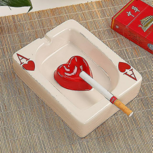 cenicero de cigarrillos de cerámica wabjtam creativo de póker, ceniceros modernos portátiles de mesa, cenicero de cigarros para exteriores — vista cenital de cenicero rectangular de cerámica crema con as de corazones en las esquinas, apoyo interior rojo en forma de corazón y dos ranuras para cigarrillos; acabado brillante y base lisa, sobre mantel de fibras; también sirve como pequeña bandeja para dulces o decoración de mesa.