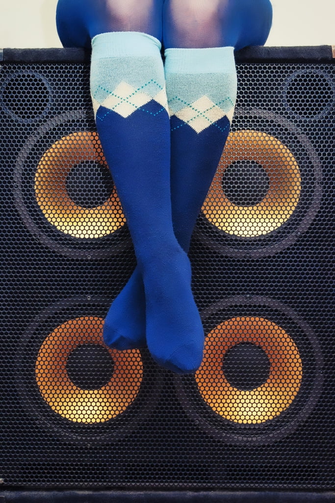 Woman in Blue Argyle Socks Sitting on Bass Speakers Rock Roll Music