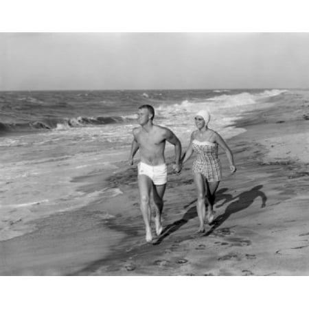 Young couple wearing swimming costumes walking on beach Canvas Art -  (24 x 36)