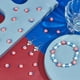 thumbnail image 4 of 1 caja de 200 cuentas de arcilla polimérica con forma de bandera, colores surtidos (blanca, roja y estrella), ideales para hacer bisutería, pulseras y manualidades. Perfectas para principiantes., 4 of 6
