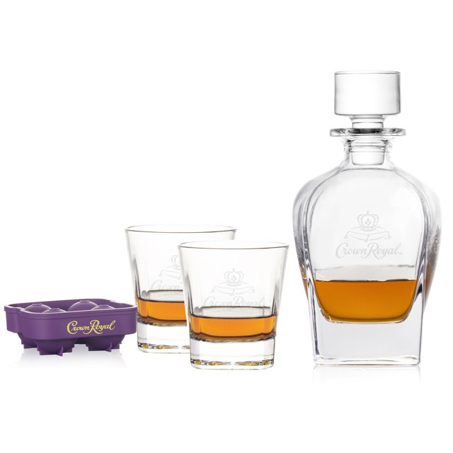 Crown Royal whisky decanter set featuring a glass decanter with amber whisky, two matching drinking glasses partially filled, and a purple Crown Royal branded ice mold.
