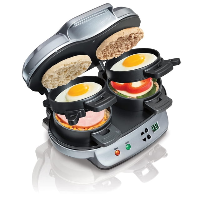 sandwichera doble hamilton beach para el desayuno Multicolor, vista 3/4 frontal con tapas abiertas mostrando dos unidades dobles con placas antiadherentes y sándwiches con huevo, jamón y vegetales; base plateada con luz indicadora y panel digital, diseño compacto para almacenamiento vertical. Prepara sándwiches caseros en 5 minutos; también suele usarse para tostar pequeños muffins ingleses.