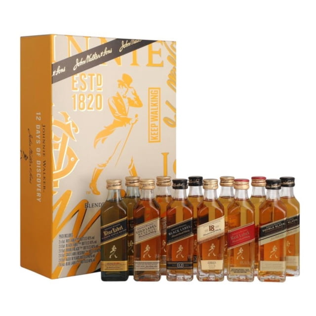 whisky johnnie walker 12 days discovery 12x 50 ml caja dorada vertical con logo del caminante y texto 'ESTD 1820', 12 botellas mini de 50 ml en fila mostrando distintas etiquetas Johnnie Walker y tonos ámbar; composición frontal sobre fondo blanco. Apto para degustación en cenas navideñas; venta sólo a mayores de edad.