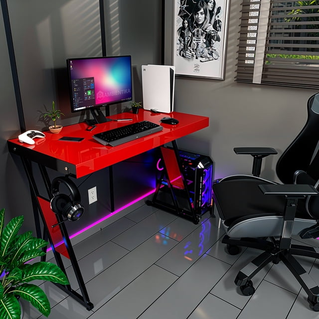 escritorio gamer oficina modelo zb 100x50cm alto brillo color rojo AMBIENTIKA, vista 3/4 frontal con superficie roja brillante y bastidor metálico negro en X, 100 cm de largo x 50 cm de profundidad y altura 75 cm, soporta hasta 60 kg; espacio para torre PC y gancho para audífonos, ideal para setup gaming o estación de trabajo compacta.