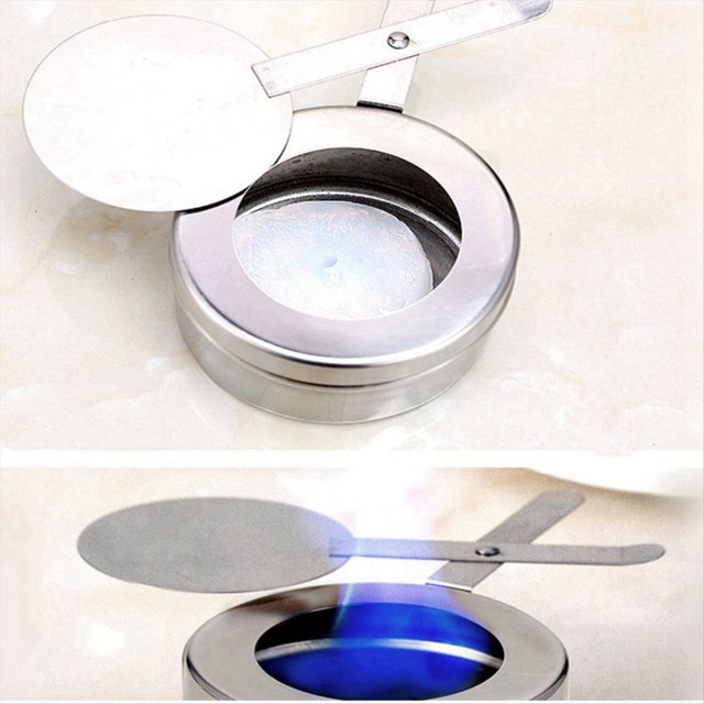rejilla de combustible para alcohol con cubierta de seguridad estufa de alcohol vertical para eventos de buffet y catering adaptabilidad a sólidos y líquidos, vista cenital y 3/4 frontal de quemador redondo de acero inoxidable plateado con tapa abatible y palanca deslizante, pastilla de combustible visible y llama azul en uso; accesorio para estufa y servicio de buffet, incluye manijas para ajuste seguro y diseño portátil adecuado para catering al aire libre y eventos.