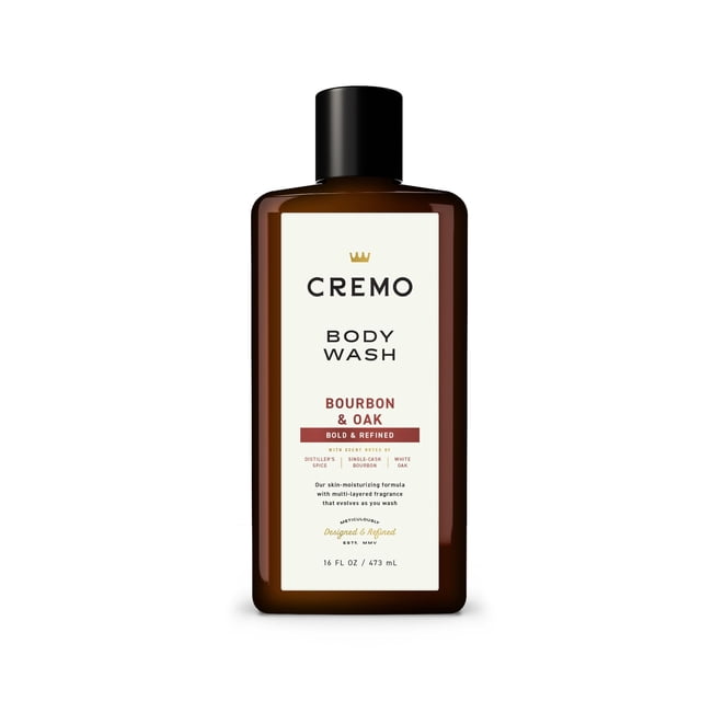 cremo all season body wash - bourbon & oak, 16 ounce frasco rectangular ámbar con tapa negra, etiqueta frontal blanca con logo CREMO y texto 'BODY WASH' y 'BOURBON & OAK'; gel de ducha masculino con aroma a bourbon y roble ahumado en el empaque. Fondo blanco minimalista.