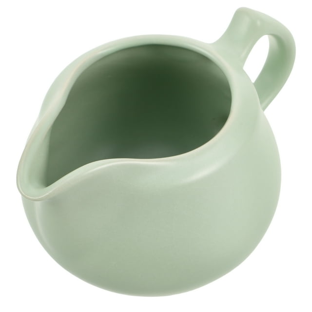 feltechelectr jarra de cerámica con asa para crema, jarra pequeña de porcelana para leche, jarra para café, salsas, ensaladas, leche, color verde Vista en 3/4 de una jarra pequeña de cerámica verde claro con boquilla vertedora frontal y asa ancha en arco; cuerpo redondeado y superficie lisa, medidas 12.00 x 8.40 x 7.40 cm; apta para servir leche, crema o salsas y adecuada para espumar leche o verter aderezos en la mesa.