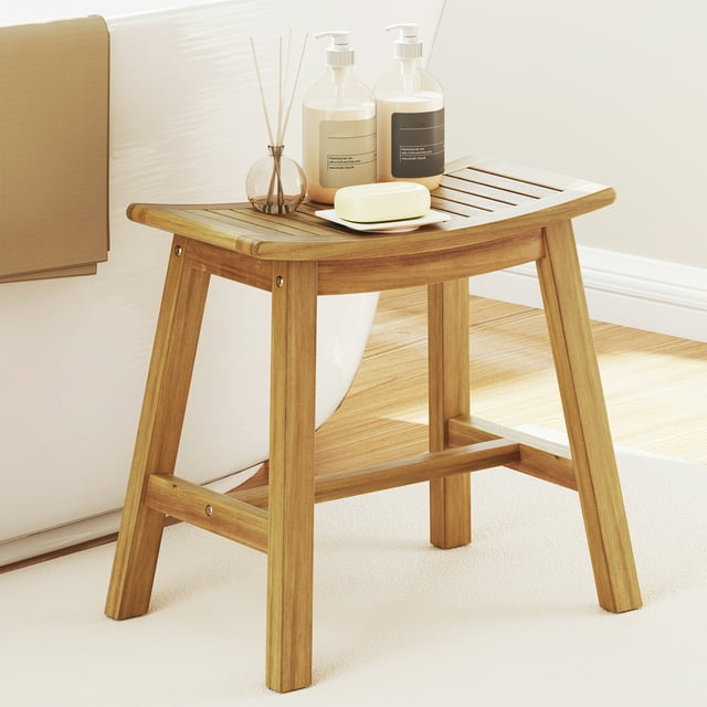Gymax Shower Bench Teak Wood Shower Stool with a curved seat, crafted from solid Indonesian teak wood. The natural wood finish and slatted seat design ensure water resistance and quick drainage, making it ideal for wet environments like bathrooms. The ergonomic seat provides comfort and support, while the H-shaped support bars enhance stability. Shown in a bathroom setting, the bench is placed near a bathtub with soap and lotion bottles on top, highlighting its multipurpose use as a bath bench or decorative piece.