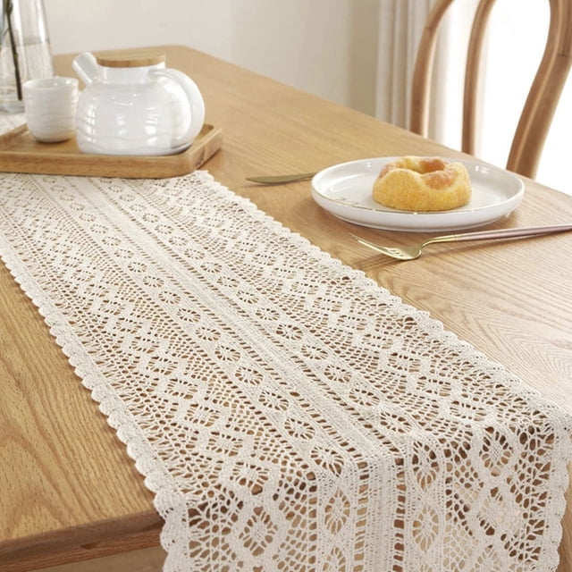 muyoka cubierta de camino de mesa de macramé de ganchillo mantel de borla de encaje tejido bohemio rectangular decoración del hogar de la boda. Camino de mesa rectangular blanco lechoso (24 x 180 cm) centrado sobre mesa de madera; tejido de algodón macramé con franjas de patrón floral hueco y borde de puntilla con borlas cortas. Escena de comedor con vajilla blanca y bandeja de madera al fondo, ideal para bodas y decoración bohemia.