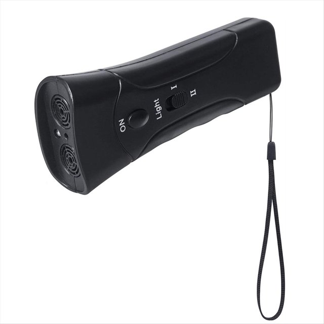 tapón de ladridos ultrasónico tapón de ladridos portátil repelente de perros de mano con luz led alimentado por batería. Dispositivo portátil negro de mano, vista 3/4; carcasa ABS con dos rejillas frontales para el emisor ultrasónico, botón ON, interruptor de modos I/II y botón 'Light', correa de muñeca incluida; emite sonido ultrasónico inaudible para humanos y luz estroboscópica para disuadir perros en exteriores; suele usarse también para alejar gatos durante caminatas.