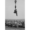 thumbnail image 1 of Still Photographer hangs suspended high above the ground on the hook of a large crane.-Fine art canvas print (20" x 30"), 1 of 1