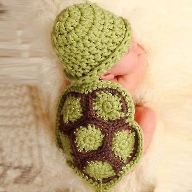 ropa tejida a crochet con forma de tortuga para bebé recién nacido, gorro, atuendo, accesorios para fotos. Recién nacido acostado boca abajo con gorro y peto de lana verde y caparazón crochet verde y marrón, textura de punto grueso; recomendado 0-4 meses y a menudo usado como accesorio para sesiones de fotos de recién nacido.