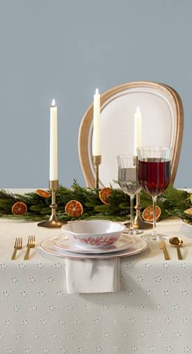 A blue dining room shows a lavish table set with candlesticks, wine glasses and a festive centerpiece.