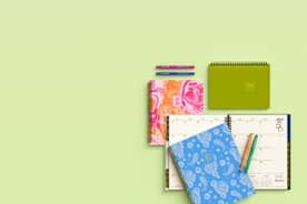 Pink, green, and blue notebooks on a green background.