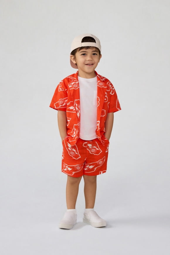 A baby wearing a matching shirt and shorts set featuring fun characters.
