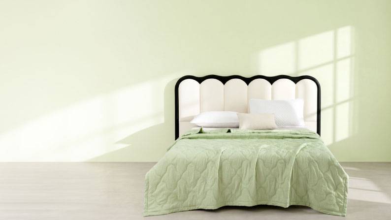 A mint green painted bedroom with a luxe dark wood headboard and matching mint green bedding.