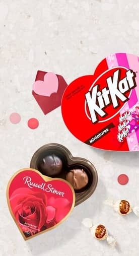 A heart-shaped KitKat box is shown next to a Russell Stover heart-shaped chocolates box.