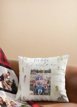 Decorative pillow with Merry Christmas text and a family photo, next to a blanket printed with multiple family photos.