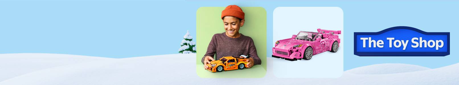 Badge that reads The Toy Shop. Child playing with a yellow Hot Wheels car and pink toy sports car shown on a snowy background.