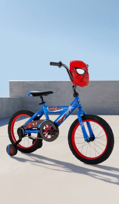 Spider-Man themed bike in blue and red with a mask on the handlebars, all in a sunny outdoor setting.