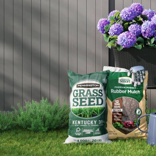 Grass seed, mulch, and potted plants on a green lawn. A grey fence is in the background. Text says: From $4.97.