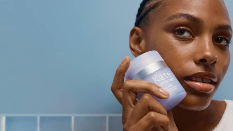 Image of a woman holding a skincare product near her face is shown.