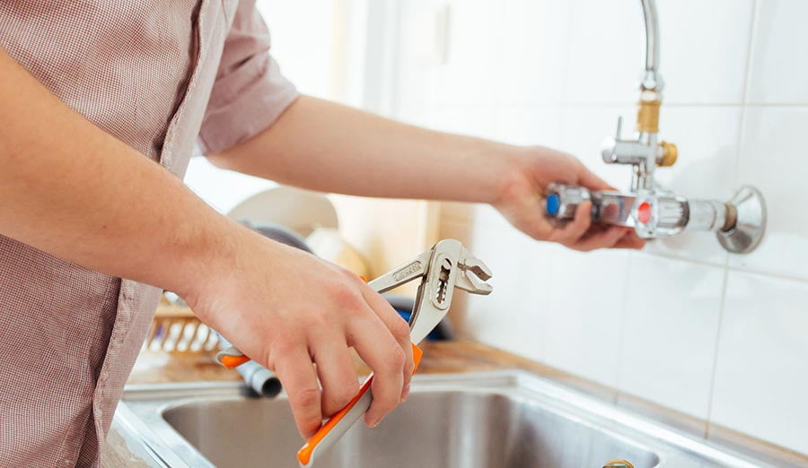 woman's hands fixing leaky faucet