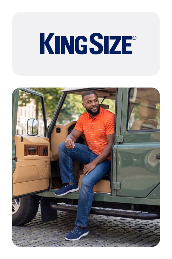 Man sitting in a green truck, wearing an orange shirt, blue jeans and blue shoes. KingSize logo.