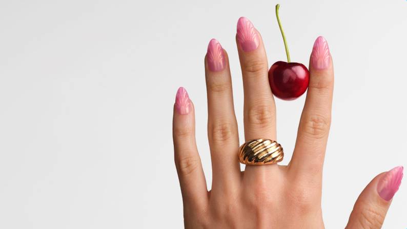 Banner featuring manicured hand with 3-D nail art press-ons and a cherry. Text: Trending now maximalist nails. Shop now.