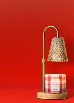 A gold candle warmer lamp is seen with a candle underneath.