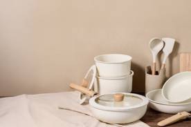 A stack of matching beige pots and dishes including a cutting board.