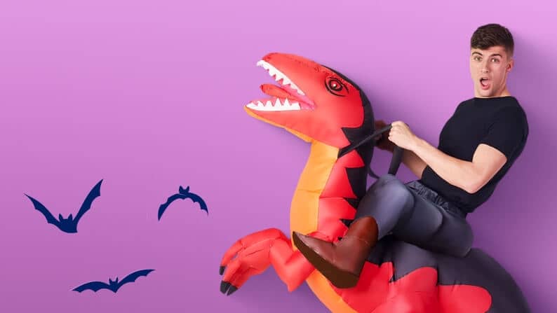 A dark-haired man dressed in a black t-shirt and wearing an inflatable T-Rex costume.