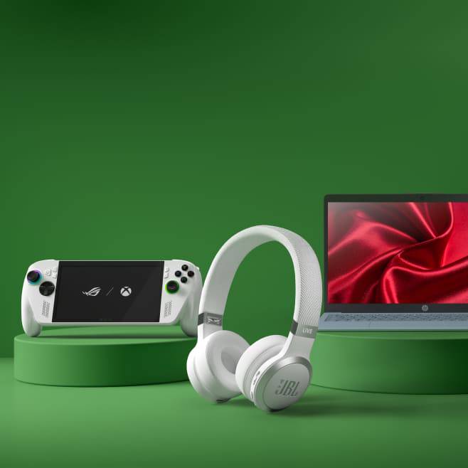 Image shows a Nintendo Switch Two, a pair of white headphones and an open laptop with a red screen display.