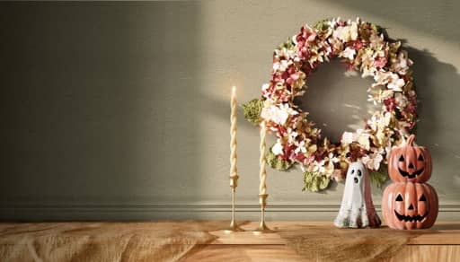 Candle holders and a wreath next to ghost and pumpkins ornaments.