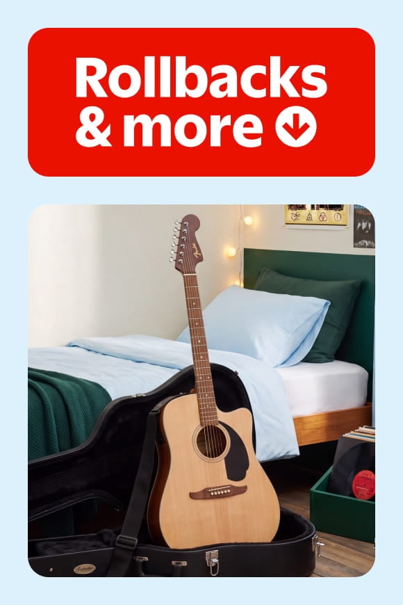 Rollbacks and more badge above an acoustic guitar in an open case at the foot of a neatly made bed.