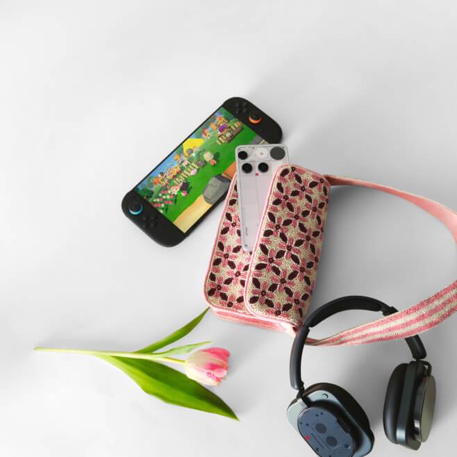 A smartphone placed inside a floral bag, black over-ear headphones, and a Nintendo Switch.