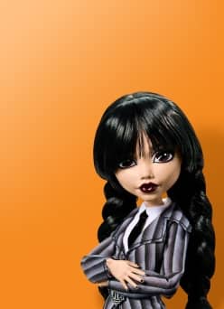 Image shows a Monster High Wednesday Addams doll on an orange background.