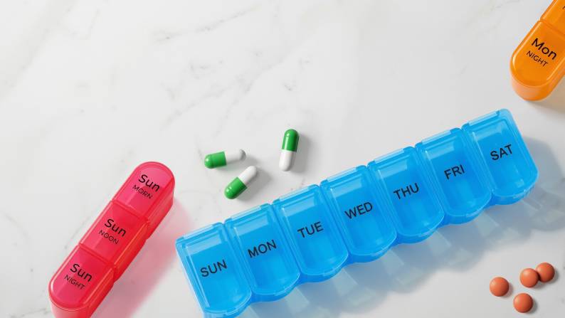 Blue-colored pill organizer with days of the week on it.
