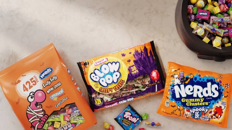 A variety bag of candy is shown next to a bag of Blow Pop Creepy Treats and Spooky Nerd Gummy Clusters.