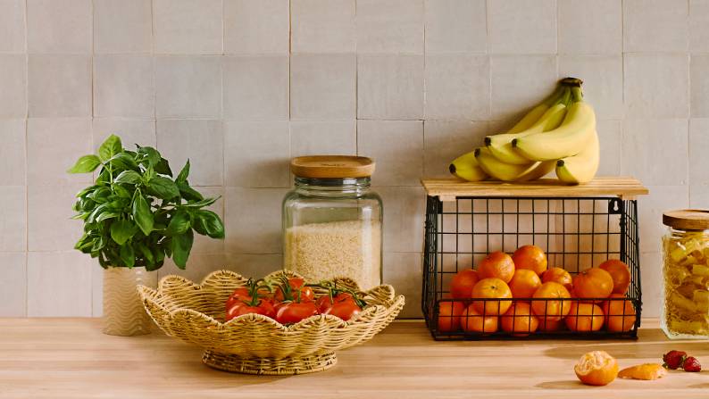 Kitchen counter with fresh produce in a woven bowl and wire shelf. Reads: Fresh ways to store. From ten ninety-seven.