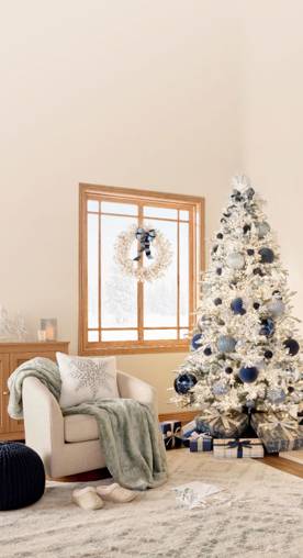 Image of a living room decorated with a flocked Christmas tree. The mantel and tree decor are all navy, light blue, and silver.