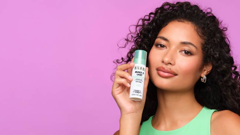 Image with pink background reading “Milani & so much more. Prime & set your makeup” and “Shop now,” featuring model holding setting spray.