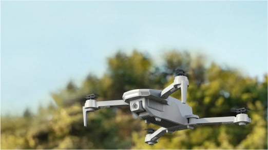 Image of a white drone flying outside.