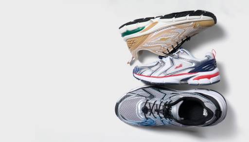 Three athletic sneakers in tan, white-and-red and metallic silver stacked diagonally against a light grey background.