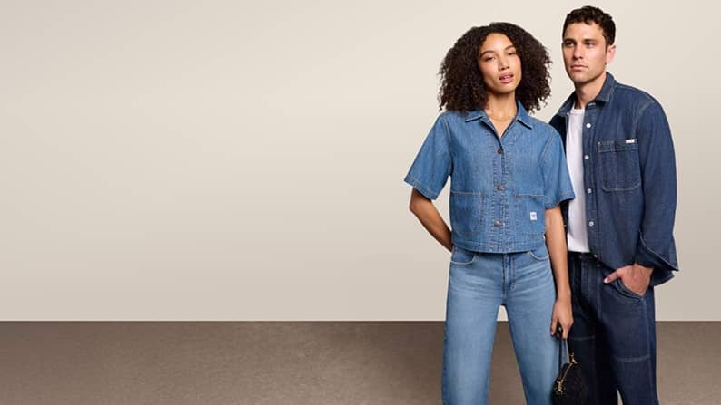 A woman and a man in denim shirts and jeans are pictured on a beige backdrop.