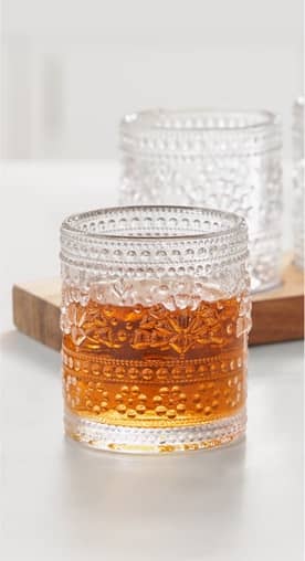 An embossed-detailed cocktail glass filled halfway is shown.