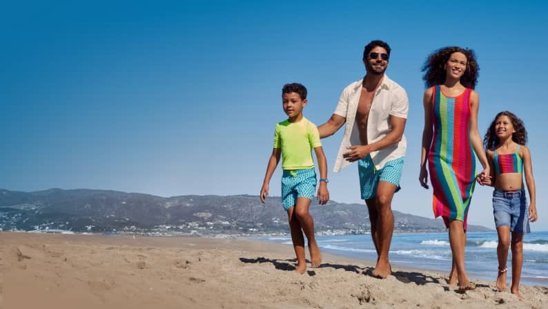 A family of four is shown walking on a beach wearing matching swim styles, from suits to coverups. From seven dollars is seen in lower left corner.